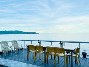 a table and chairs on a deck next to the water at Bohol Seafront Villa Pasan Cove a resort homestay in Guindulman +23 photos