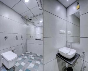 a white bathroom with a toilet and a sink at Hotel Arts International in Mumbai