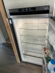 an empty refrigerator with its door open in a kitchen at Chambre Guernesey - Quai des Ormes in Barneville-Carteret