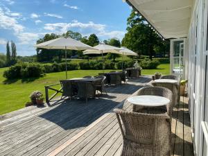 a wooden deck with tables and chairs and umbrellas at Stegeborg Trädgårdshotell in Stegeborg