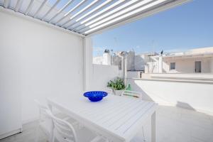 滨海波利尼亚诺Pausa Mare Lodge的阳台上的一张白色桌子上放着一个蓝色的碗