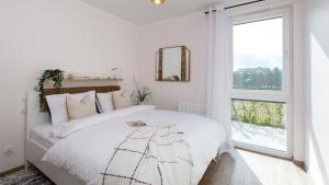 a white bedroom with a bed and a window at Baltic Line - Sobieszewski Raj in Gdańsk