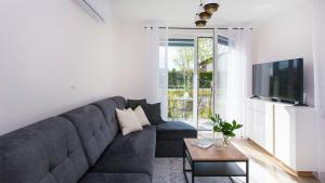a living room with a blue couch and a tv at Baltic Line - Sobieszewski Raj in Gdańsk +4 photos