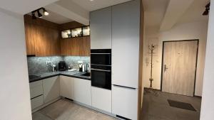 a kitchen with white cabinets and black appliances at Cozy Flat by High Tatras! in Poprad