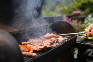 a person cooking meat on a grill with tongs at Mladenović Kuća in Kopaonik