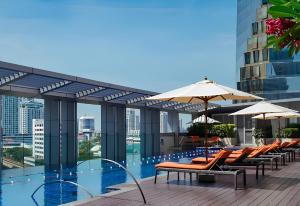 a pool with chairs and umbrellas on a building at Bangkok Marriott Hotel Sukhumvit in Bangkok
