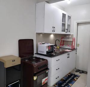 a small kitchen with a stove and white cabinets at Lavish Apartment with Swimming Pool Ongata Rongai in Nairobi