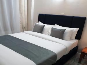 a large bed with white sheets and pillows at Lavish Apartment with Swimming Pool Ongata Rongai in Nairobi