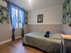 a bedroom with a bed and a window with blue curtains at Le grand écrin Vichyssois in Vichy