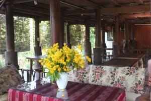 a vase filled with yellow flowers on a table at Nhà sàn Mường in Ba Vì