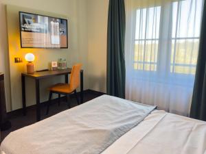 a bedroom with a bed and a desk and a window at Coffee Fellows Hotel Frankfurt Airport-Langen in Langen