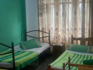 two beds in a room with green walls and curtains at Divine Homestay Kandy in Kandy