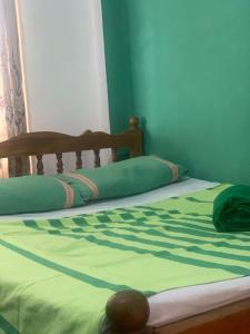 a bed with a green blanket on top of it at Divine Homestay Kandy in Kandy