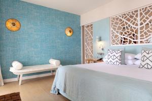 a bedroom with a large bed and a bench at Hotel Honucai in Colònia de Sant Jordi