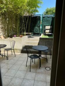 a patio with four chairs and tables and a table and chairs at Le Jardinet - With office in the city center! in Castelnau-le-Lez