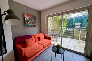a living room with a red couch and a sliding glass door at Le Jardinet - With office in the city center! in Castelnau-le-Lez