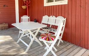a picnic table and two white chairs on a porch at 3 Bedroom Cozy Home In Tingstäde in Tingstäde