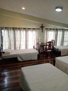 a room with three beds and a table and window at VG Bed and Breakfast in Sampong