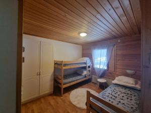 a bedroom with two bunk beds and a wooden ceiling at Kaamasen Kievari in Kaamanen
