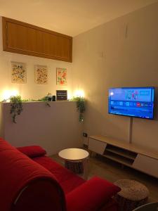 a living room with a red couch and a flat screen tv at Capalbio Relaxhouse in Capalbio