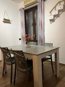 a dining room table with chairs and a vase with flowers at Capalbio Relaxhouse in Capalbio