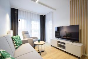 a living room with a couch and a flat screen tv at Apartament Szmaragd&Perła by LookAp - parking gratis! in Poznań