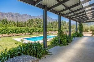 an estate with a swimming pool and mountains in the background at Franschhoek Rose Cottages in Franschhoek