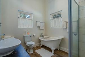 a bathroom with a tub and a toilet and a sink at Franschhoek Rose Cottages in Franschhoek +55 photos