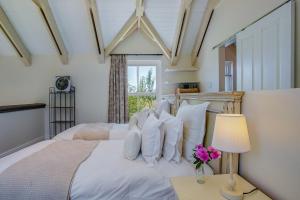 a bedroom with a white bed with white pillows at Franschhoek Rose Cottages in Franschhoek