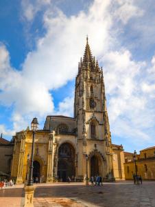 a large building with a clock tower in a city at Apartamento Oviedo Centro in Oviedo