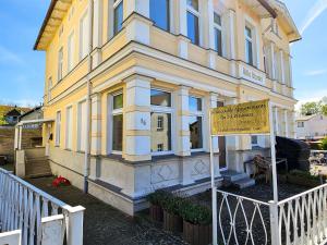 a yellow building with a sign in front of it at Villa Utpatel Whg 01 in Ahlbeck