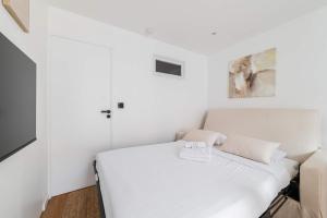 a white bedroom with a bed and a couch at Escapade urbaine Appartement Mairie des lilas in Les Lilas