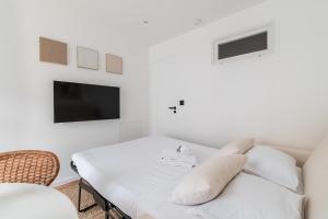 a white living room with a couch and a tv at Escapade urbaine Appartement Mairie des lilas in Les Lilas