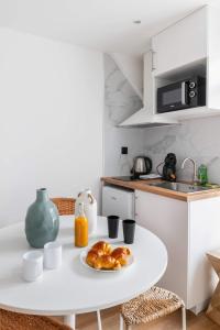 a white kitchen with a table with a plate of croissants at Escapade urbaine Appartement Mairie des lilas in Les Lilas