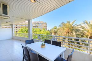a white table and chairs on a balcony with palm trees at Rentalmar Royal in Salou