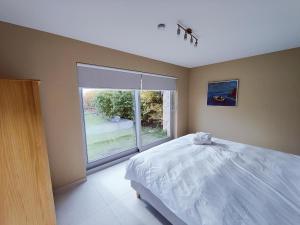 a bedroom with a bed and a large window at Het Weiland Villa Jersey in Damme