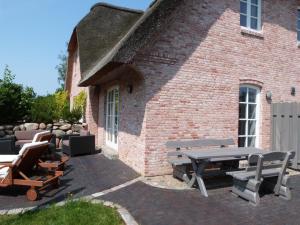 a patio with picnic tables and chairs in front of a brick building at Dat Lilli und Anni Huus in Böhl