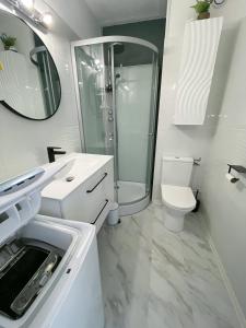 a white bathroom with a shower and a toilet at évasion méditerranéenne - vue mer - plage in Le Barcarès