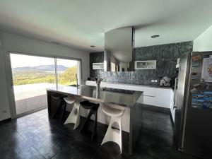 La cuisine est équipée d'un comptoir avec évier et d'un réfrigérateur. dans l'établissement Magnifique villa VUE MER, piscine, 190 m2 , 4 chb, 3 sdb, clim, à Bastelicaccia
