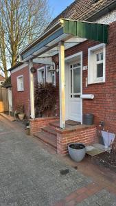 a brick house with a front porch with a white door at Ferienhaus Frerichs 15209 in Leer