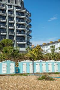 a row of beach huts on the beach with a tall building at The View Hotel in Eastbourne