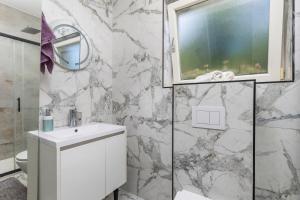 a white bathroom with a sink and a mirror at Vila Lux 3 in Rijeka