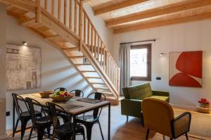 a living room with a table and chairs and a staircase at Apartaments Casa Maragall in Sant Joan de les Abadesses +28 photos