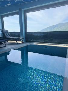 a swimming pool with two chairs and a window at S-Penthouse in Herceg-Novi