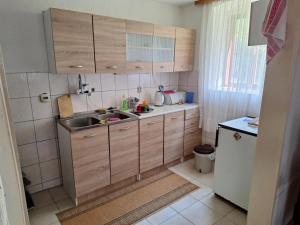 a small kitchen with wooden cabinets and a sink at Kuća Knežević in Mlječanica