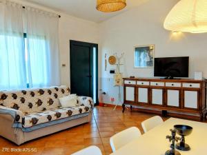a living room with a couch and a tv at Appartamento in villa Porto Pollo in Porto Pollo