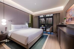um quarto com uma grande cama branca e uma escrivaninha em 杭州西湖桔子水晶酒店 em Hangzhou mais 20 fotografias