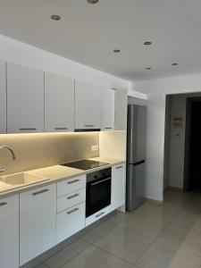 een keuken met witte kasten, een wastafel en een fornuis bij Ammouses Apartment in Potamós