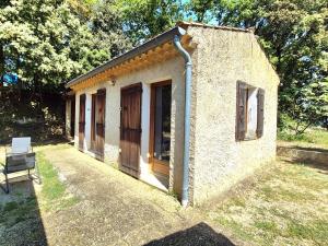 Un pequeño edificio con una puerta y un banco. en Maison indépendante avec Jardin, Studio de 26m2 tout équipé avec Climatisation réversible, en Rochegude