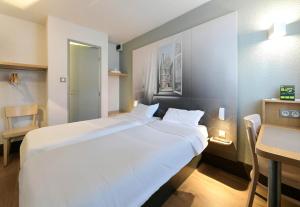 a large white bed in a room with a table at B&B HOTEL Alencon Nord in Alençon +35 photos